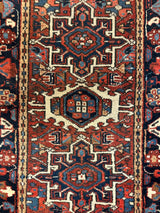 Close-up of a vintage Persian Karaja Heriz runner with bold geometric medallions in red, blue, and cream colors on a detailed patterned field