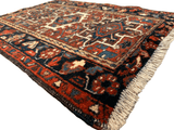 Detailed close-up of a vintage Persian Karaja Heriz runner rug in rich reds, blues, and creams with geometric patterns and fringed edges.