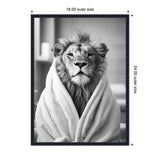 Black and white portrait of a lion wrapped in a soft towel, set against a blurred bathroom background, framed with a beaded black frame.