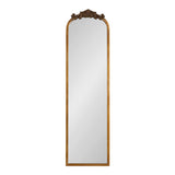 Tall rectangular mirror with an arched top, framed in warm wood, featuring detailed dark ornamental carving at the arch apex.