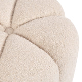 Close-up of the off-white, textured fabric of a round tufted ottoman with a central button detail and soft, curved segments.