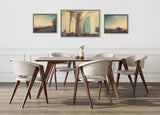 Dining room with modern wooden table and six cream-colored chairs, featuring three framed canvases on the wall showing beach and surfboard scenes.