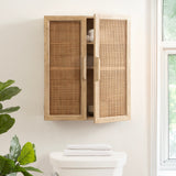 Wall-mounted wooden cabinet with two rattan panel doors, one slightly open revealing interior shelves, positioned above a white sink and next to a window and green plant.
