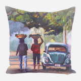 Impressionistic painting on pillow of two people carrying baskets on their heads walking past a blue vintage car under green tree foliage with soft, warm lighting.