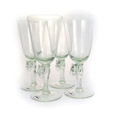 Four clear glass wine glasses each with an elephant-shaped stem detail, grouped closely against a white background.