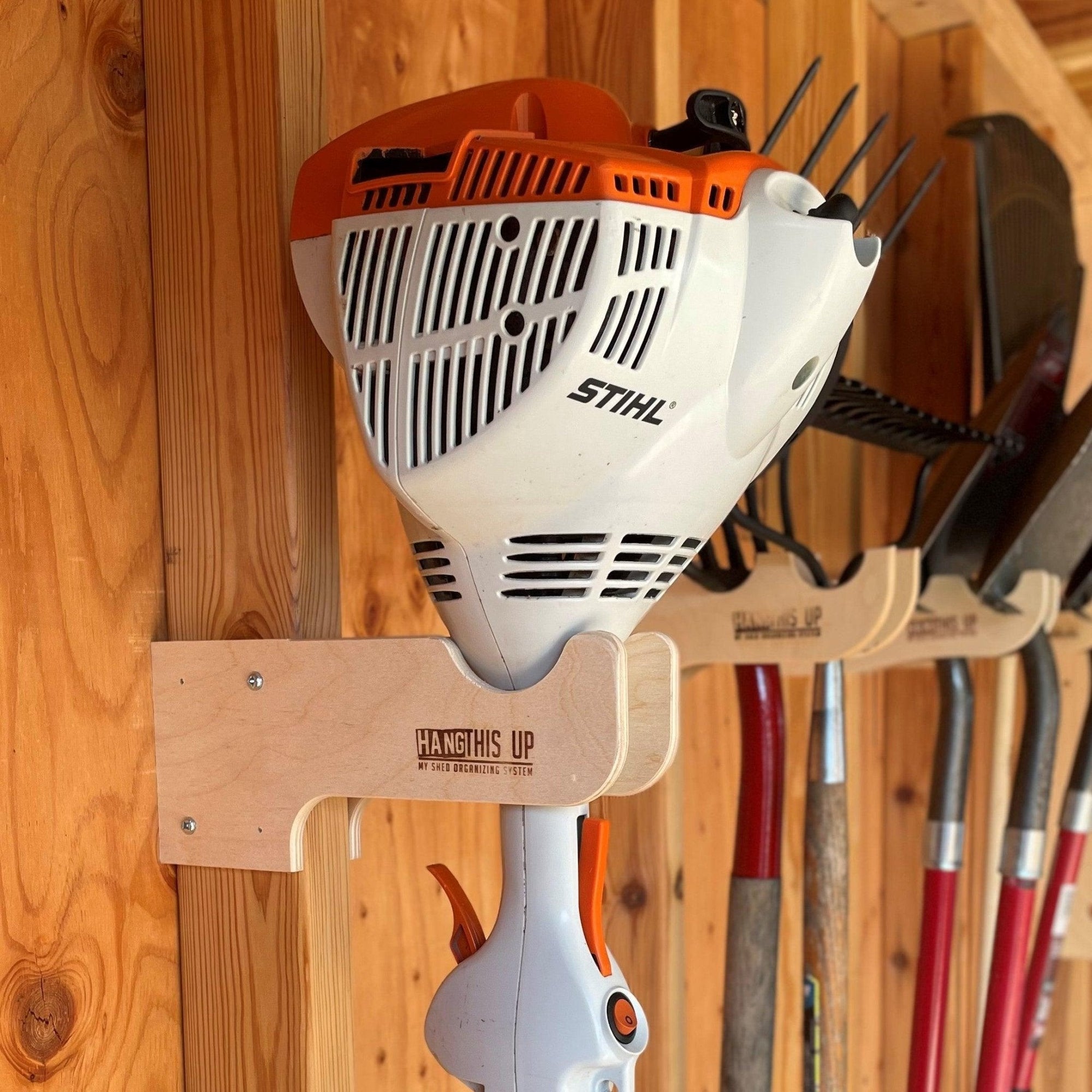 Stud mounted weed wacker organizer rack installed in a shed holding a weed wacker