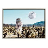 Astronaut standing in a desert cactus field under a pale blue sky with a large detailed moon, surrounded by distant mountains.