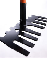 Close-up of a black metal rake head with wide, flat tines and an orange wooden handle, shown against a white background.
