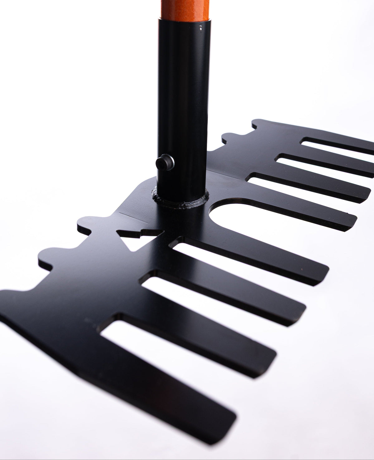 Close-up of a black metal rake head with wide, flat tines and an orange wooden handle, shown against a white background.