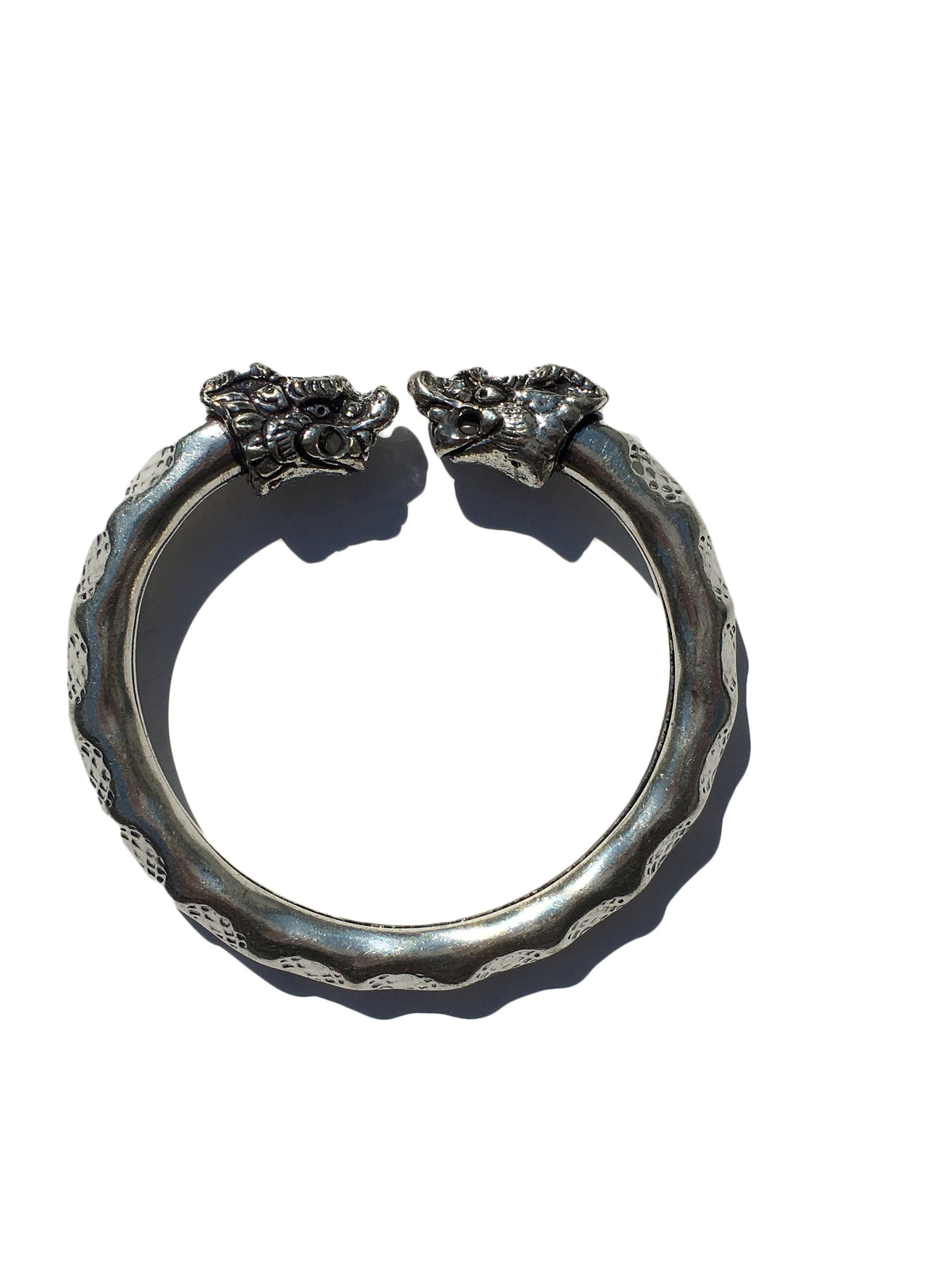 Antique Norse Viking bracelet in silver with two detailed lion heads facing each other and a waved pattern along the circular band.