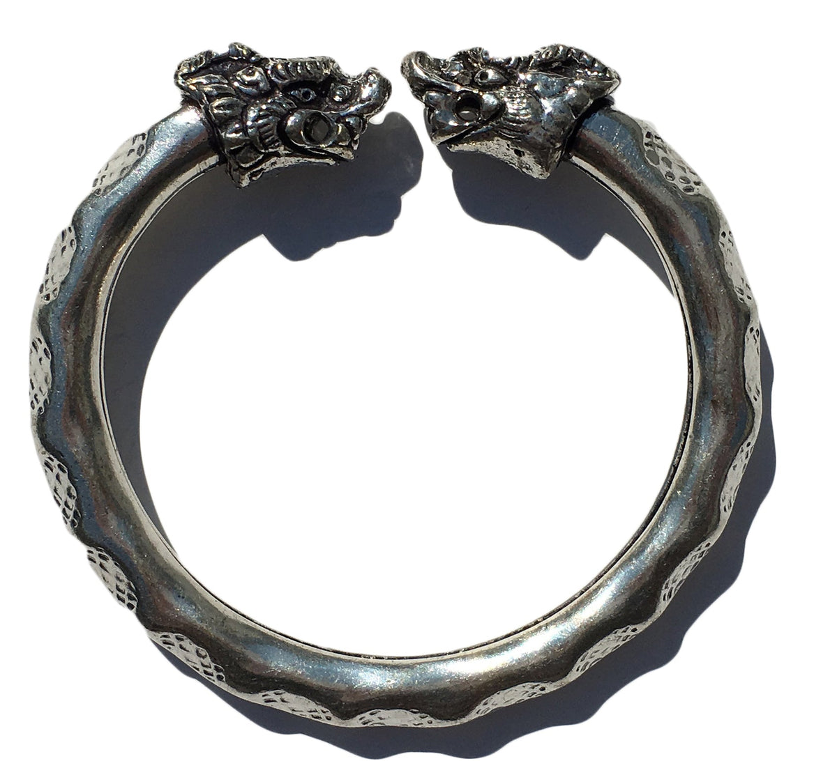 Antique Norse Viking Bracelet showing two lion heads twisting around with waved pattern on white background
