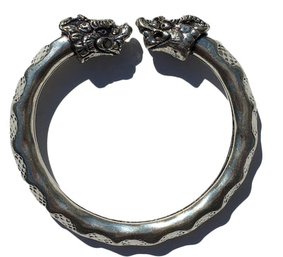 Antique Norse Viking Bracelet showing two lion heads twisting around with waved pattern on white background