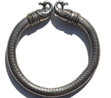 Antique Viking bracelet featuring detailed Norse peacock head terminals and a dotted, textured silver band forming a rigid circular shape.