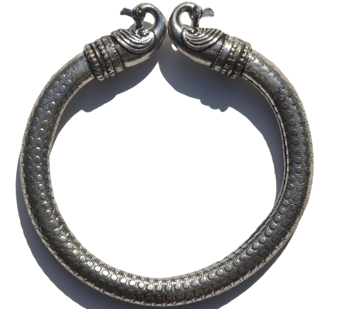 Antique Viking bracelet featuring detailed Norse peacock head terminals and a dotted, textured silver band forming a rigid circular shape.