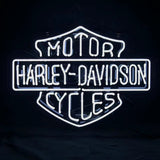 White neon sign shaped like the Harley-Davidson Motor Cycles shield logo glowing against a black background.