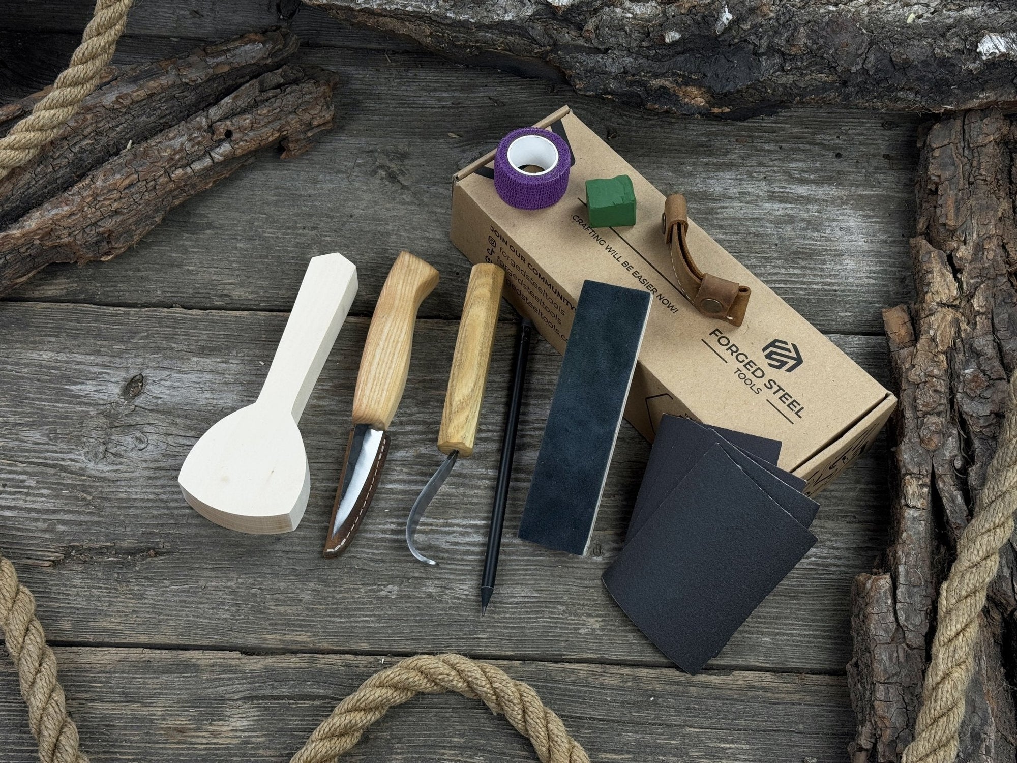 Beginner wood carving kit with sloyd knife, hook knife, wooden blank, sandpaper, sharpening board, pencil, and finger wrap