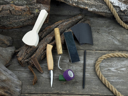 Beginner wood carving kit with sloyd knife, hook knife, wooden blank, sandpaper, sharpening board, pencil, and finger wrap