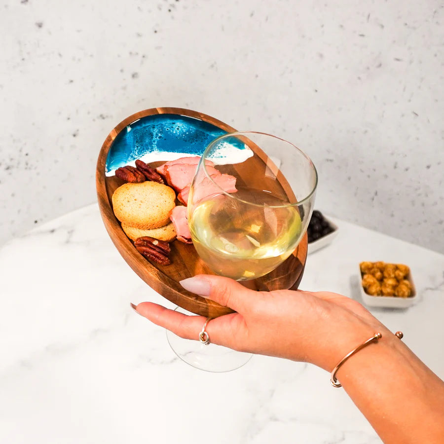 Hand holding a glass of white wine with a Wine & Appetizer Tray on a marble surface