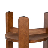 Close-up of a round wooden side table with three vertical legs extending above the circular top, each capped with a black knob.