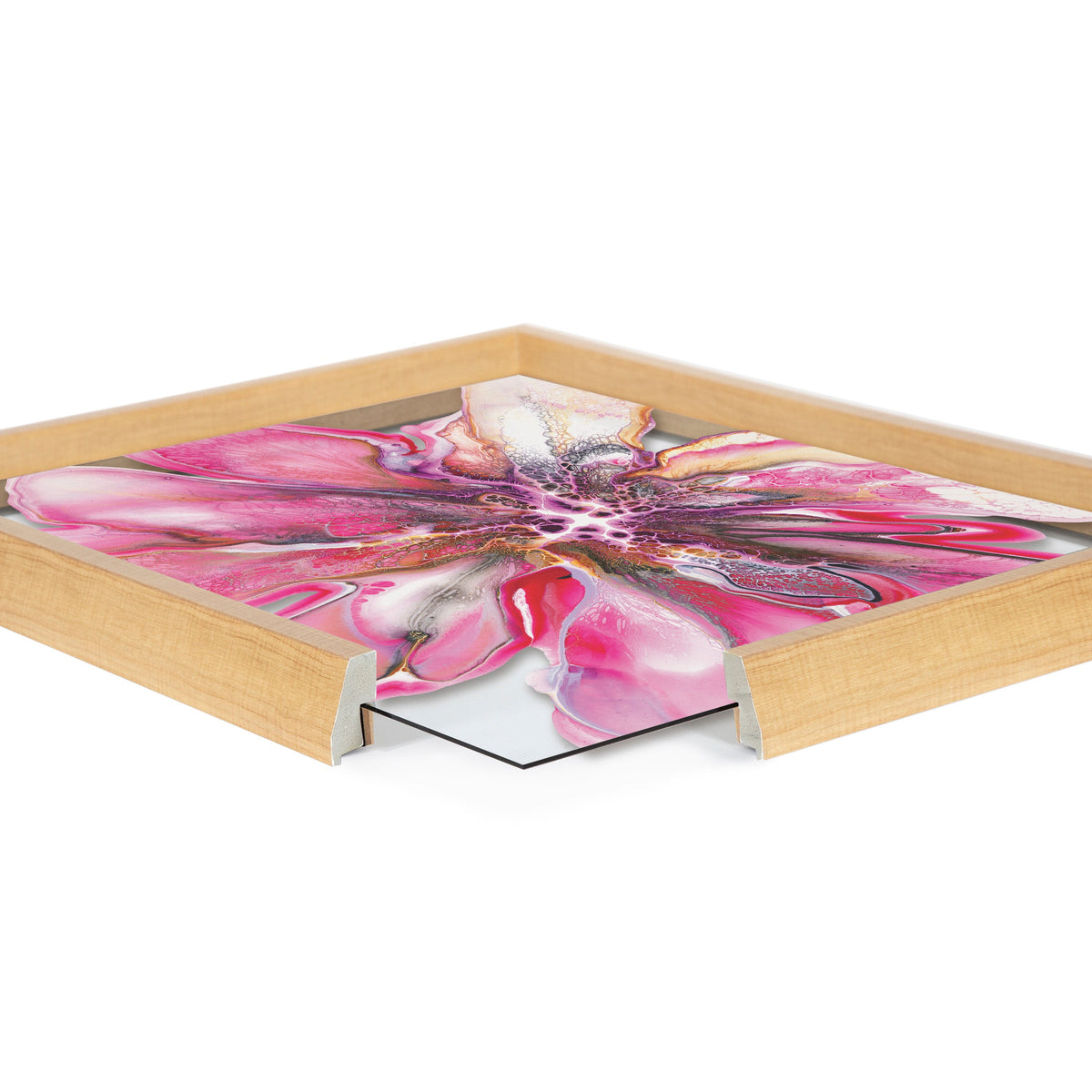 Close-up of framed art featuring a vibrant pink flower with abstract petals inside a light wood frame with mitered corners, shown from an angled top view.