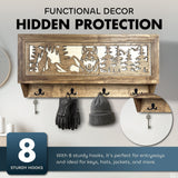 Wooden wall-mounted coat rack with eight black metal hooks and a carved panel showing a wolf in a pine forest, featuring a hidden compartment behind the panel with a key lock.