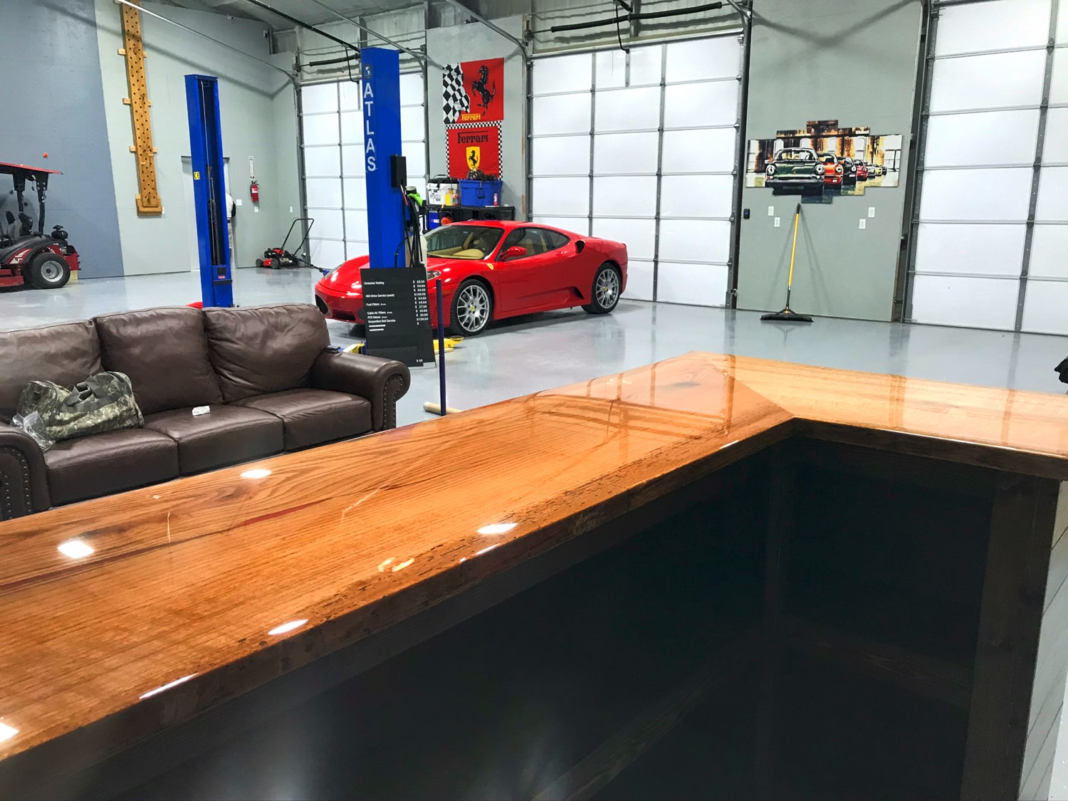 Modern car showroom with a red sports car, brown leather sofa, and wooden reception desk.