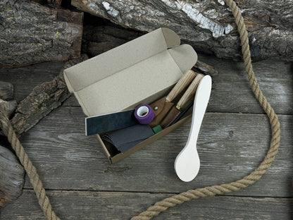 Wood Whittling Starter Kit with sloyd knife, hook knife, wooden blank, sandpaper, sharpening board, pencil, and finger wrap