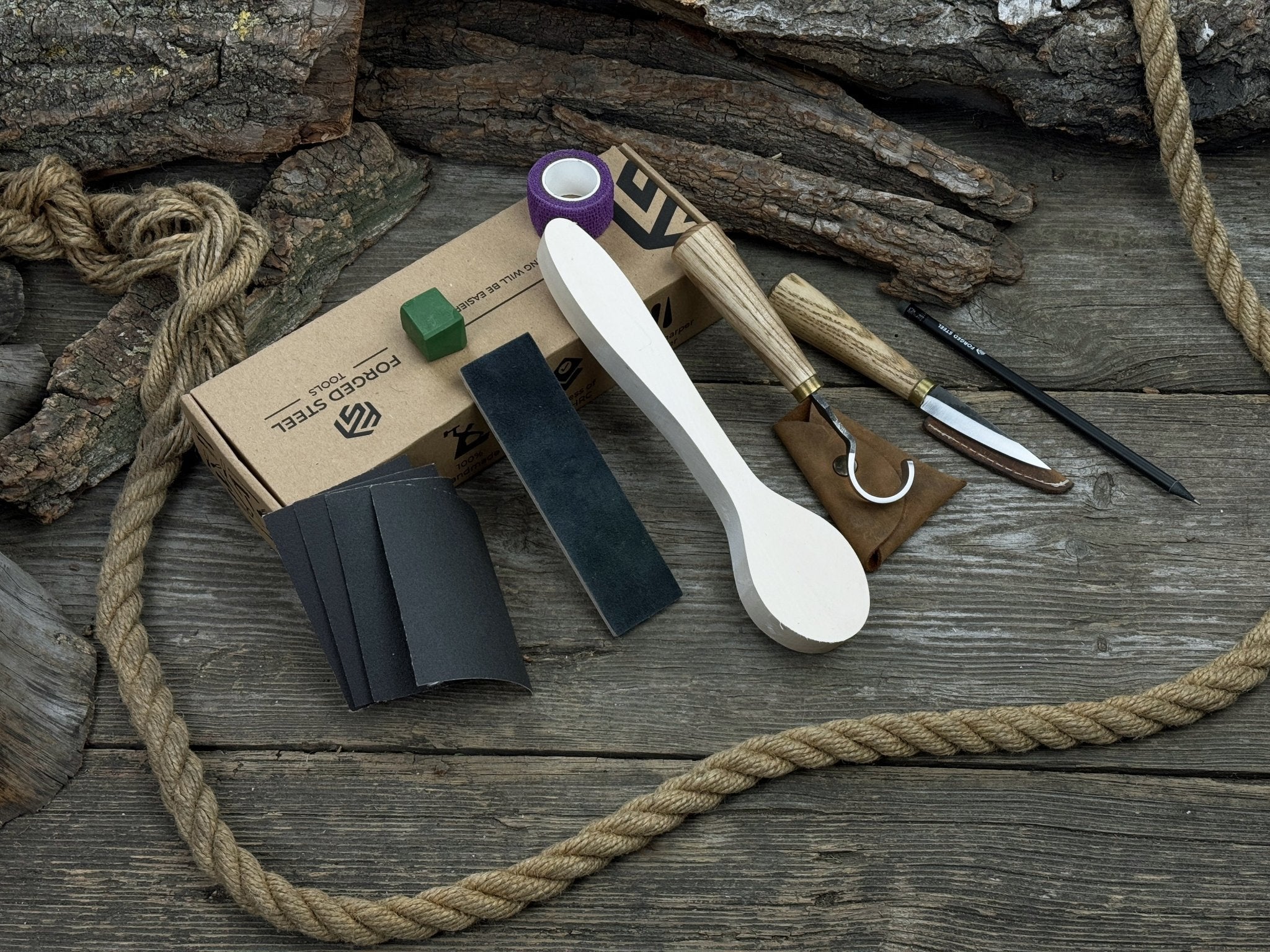 Wood Whittling Starter Kit with sloyd knife, hook knife, wooden blank, sandpaper, sharpening board, pencil, and finger wrap