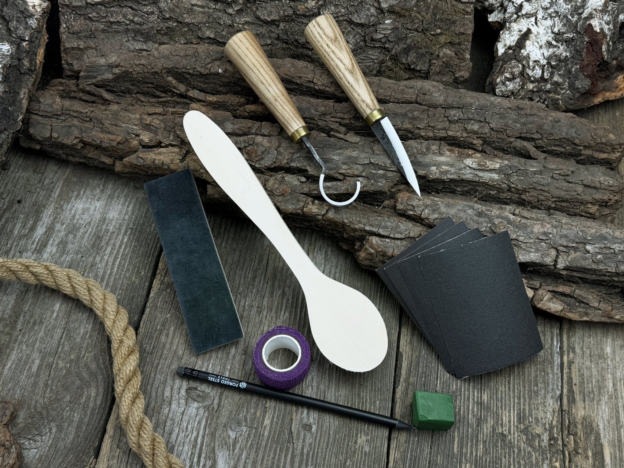 Wood Whittling Starter Kit with sloyd knife, hook knife, wooden blank, sandpaper, sharpening board, pencil, and finger wrap