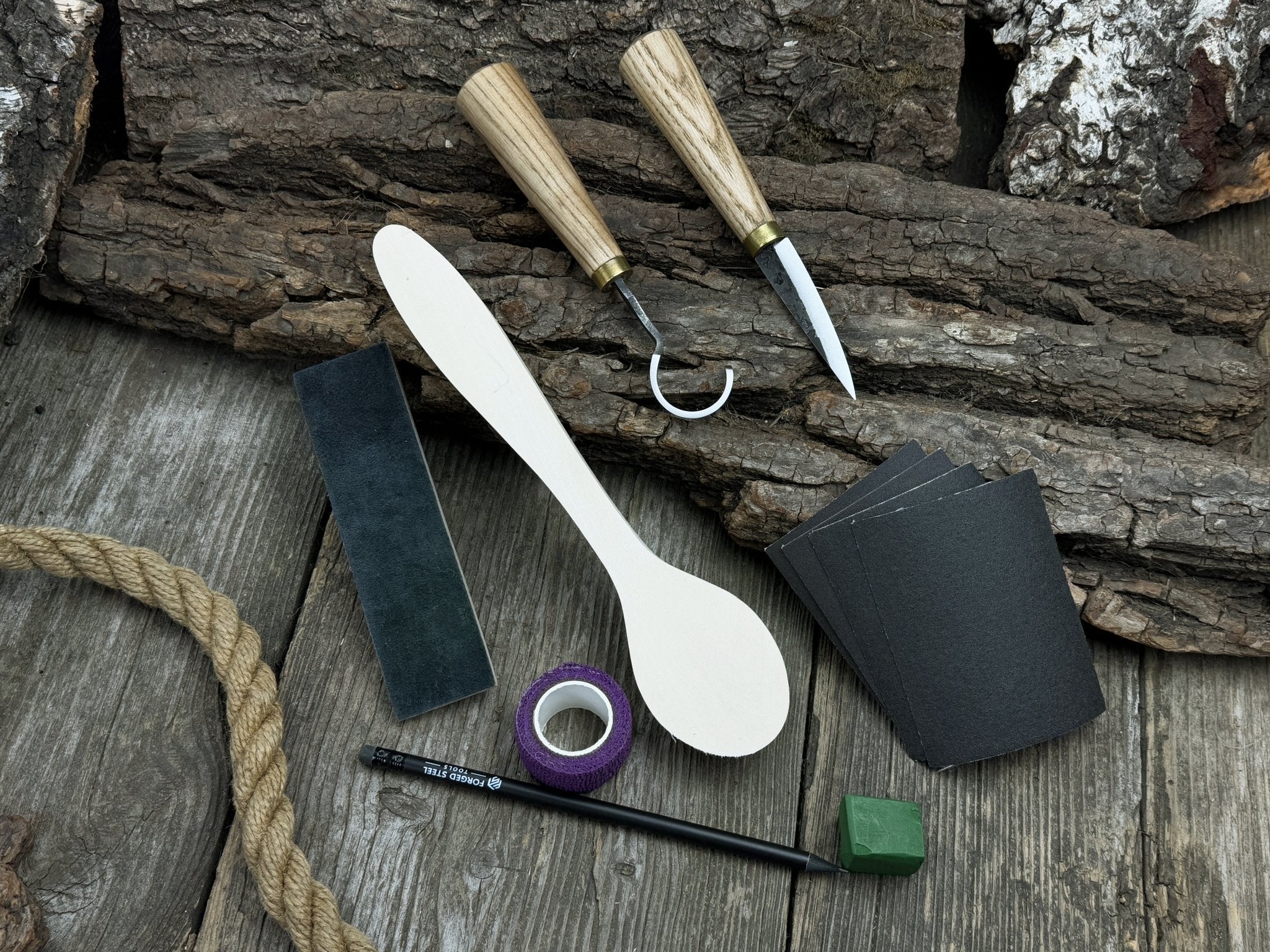 Wood Whittling Starter Kit with sloyd knife, hook knife, wooden blank, sandpaper, sharpening board, pencil, and finger wrap