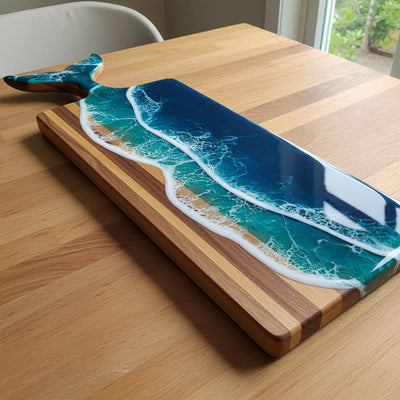 Whale Tail Ocean Resin Charcuterie Board made of acacia wood with blue ocean resin and matching cheese knife