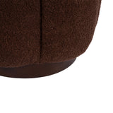 Close-up of dark brown textured fabric upholstery on a round ottoman with a smooth, slightly visible wooden base beneath.