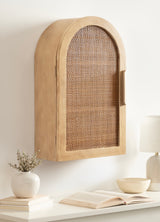 Light wood wall cabinet with an arched top and woven rattan front panel, mounted above a white shelf with neutral decor items.