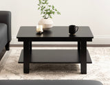 Rectangular black wood coffee table with a lower shelf, decorated with a white textured vase with green branches, a white candle, and a black mug, on a neutral patterned rug.