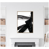 Black abstract brush strokes crossing over white background on a vertically framed canvas above fireplace in a minimalist white room with wicker baskets on shelves.