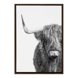 Black and white close-up of a Highland cow facing forward with long shaggy hair partially covering its eyes and a single prominent horn curving leftward.