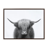 Black and white frontal portrait of a Highland cow with long shaggy hair covering its eyes and wide curved horns, centered against a plain white background.