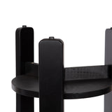 Close-up of the underside of a round black wooden side table showing four vertical legs extending above the circular shelf base.