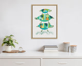 Framed canvas artwork of three stylized turtles stacked vertically, in teal, green, yellow, and blue geometric shapes, hanging on a white wall above a white cabinet with books, plants, and decor.