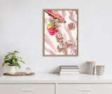 Framed canvas of a hand with black nail polish and ring poised over billiard balls on a shiny pink satin surface beside a colorful cocktail with garnish.