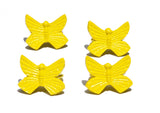 Set of four yellow butterfly-shaped napkin rings with textured wings, arranged in a square on a white background.