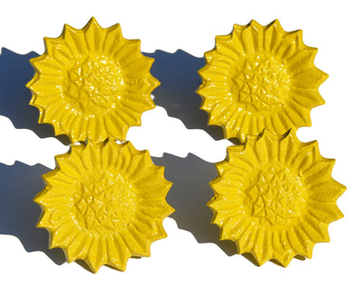 Set of four Vibhsa sunflower yellow napkin rings arranged on a white dining table