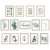 A collection of 14 framed art prints arranged in three rows, featuring watercolor fruits, plants, mushrooms, minimalistic mountain landscapes, abstract faces, a meditative figure, a fox with a cup, and a detailed boombox sketch.