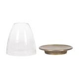 Clear textured glass cloche next to a round, shallow metal candle holder with an antique bronze finish and slightly raised rim.