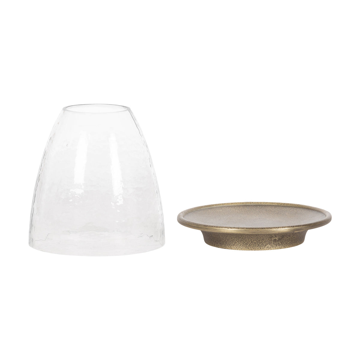 Clear textured glass cloche next to a round, shallow metal candle holder with an antique bronze finish and slightly raised rim.