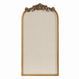 Tall arched pinboard with beige fabric surface and a carved wood frame featuring an ornate floral design at the top center.