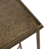 Close-up of a corner of a metal side table with a hammered texture and a warm bronze finish on the tabletop and round leg