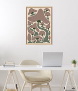 Abstract art print featuring various stylized mushrooms in muted brown and green tones with soft, organic shapes in a light wooden frame hung on a white wall above a modern white desk.