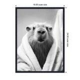 Black and white close-up portrait of a capybara wrapped in a towel looking directly at the camera with a calm expression