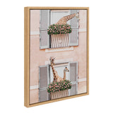 Framed canvas art showing two giraffes poking heads out of two sets of gray window shutters with pink flower boxes on a peach wall background.